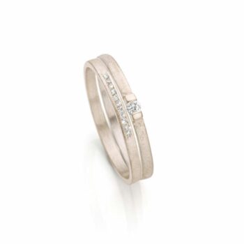 Moderne en tijdloze combinatie van matte verlovingsring met één diamant en trouwring met elf diamantjes.