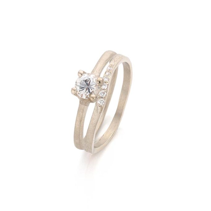 Sierlijke minimalistische combinatie van trouw -en verlovingsring met 6 kleine diamanten en één grote in gepolijst opzetstuk.