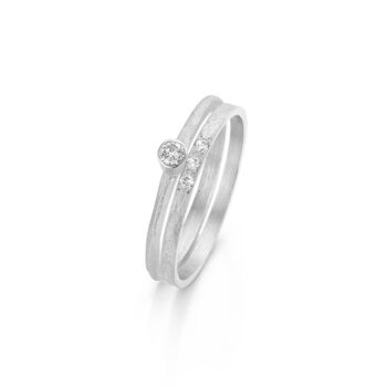Organic white gold combination with matte finish, polished edges and three small diamonds with one larger one above.