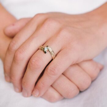 Fonkelende witgouden verlovingsring met matte afwerking met een diamant tussen twee gepolijste details.