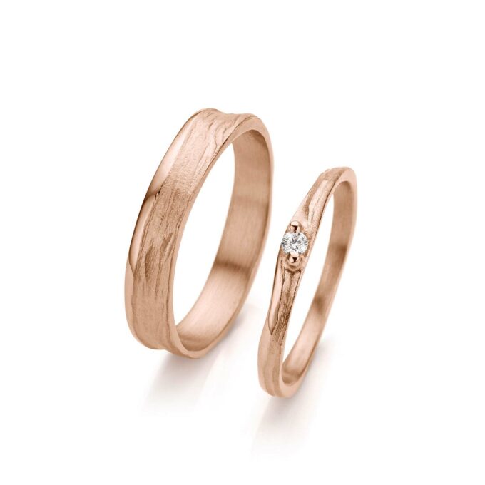 Dainty rose wedding rings with matte irregular finish, thick polished edges and one diamond in the ladies ring.