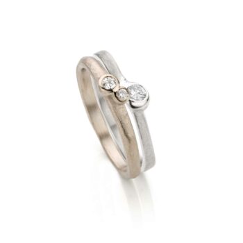 Light and organic combination wedding -with engagement ring with three diamonds, a matte finish and polished details.