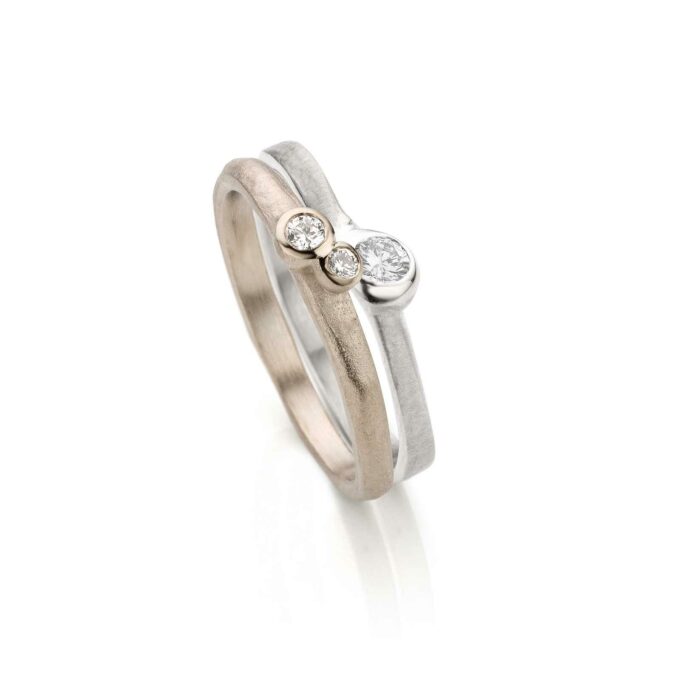 Lichte en organische combinatie van trouw -met verlovingsring met drie diamantjes, een matte afwerking en gepolijste details.