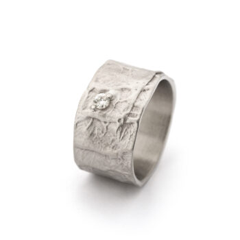 Brede handgemaakte gouden ring met ruwe textuur en één centrale diamant van 0,075 ct. Verkrijgbaar in vier kleuren goud