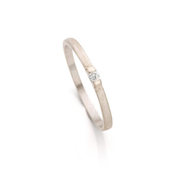 Witgouden minimalistische verlovingsring met volledig matte afwerking en een kleine diamant tussen twee gepolijste details.