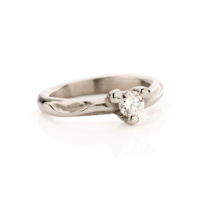 Betoverende witgouden verlovingsring met organisch lopende matte en gepolijste details en een diamant in een gepolijst sluitstuk.
