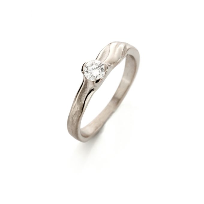 Een organische witgouden verlovingsring met een matte afwerking, gepolijste details, en een diamant als accent.