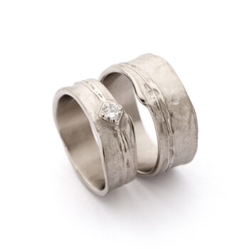 Organic wide wedding rings with polished details and diamond in ladies ring in champagne gold.