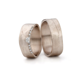 Brede elegante champagnegouden trouwringen met een grote diamant te midden van kleine diamantjes in de ring voor dames.