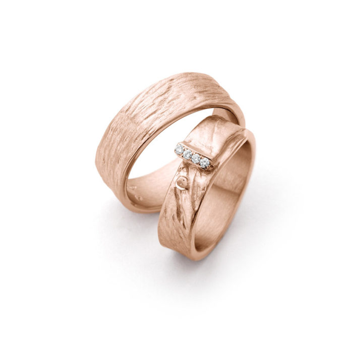 Roségouden moderne trouwringen met een oneffen, mat oppervlak, gepolijste randen en vier diamanten.