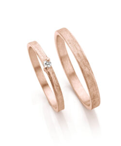 Roségouden simpele trouwringen, glinsterend oneffen oppervlak met diamant in damesring.