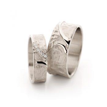 Playful white gold wedding rings with matte surface with dents, polished pieces and six diamonds.